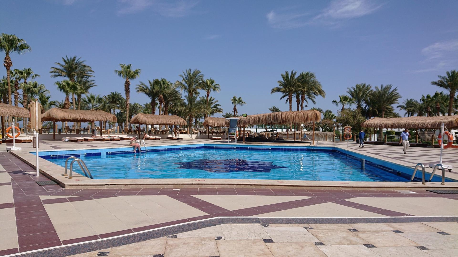 Großer Pool des Meraki Resort Hurghada mit Sonnenliegen und Palmen
