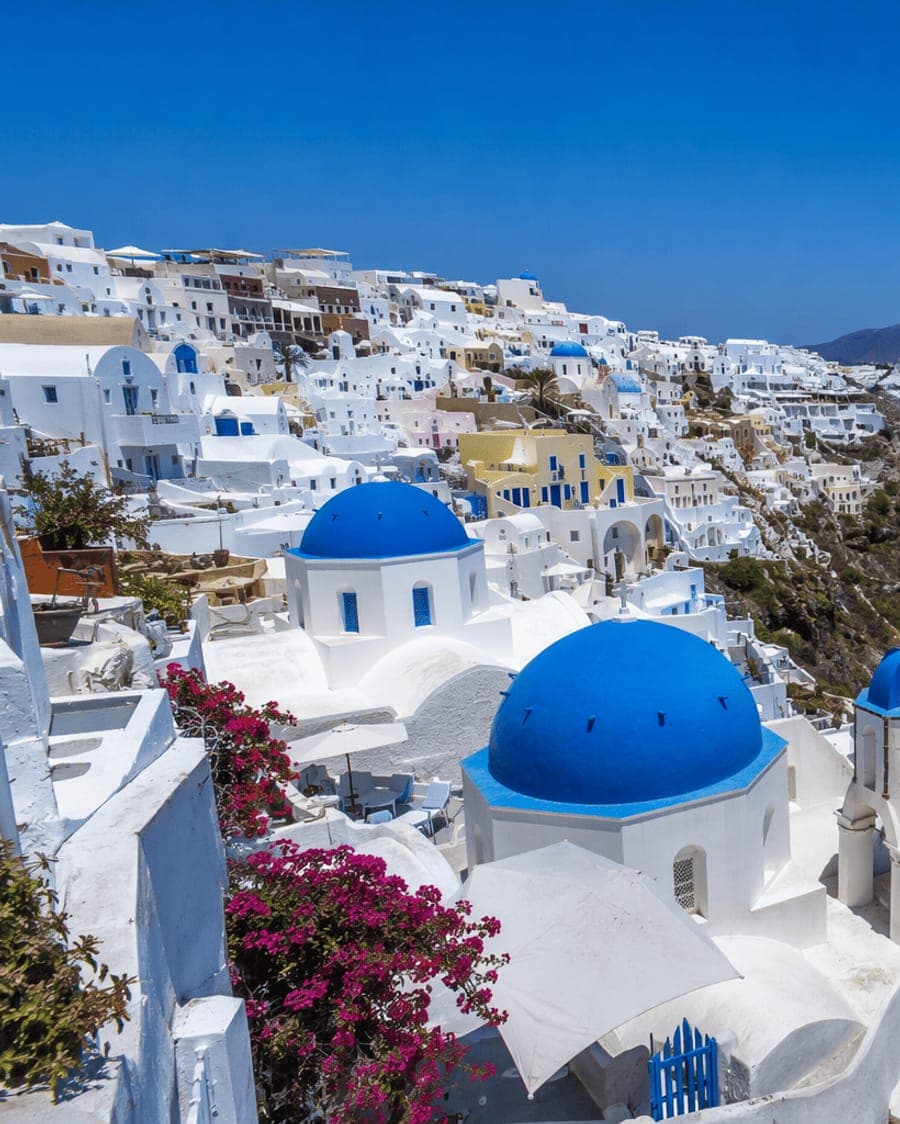Oia, Santorini - Günstige Flugreisen und Pauschalreisen Blaue Kirchenkuppeln von Oia auf Santorini mit Blick auf die Ägäis – günstige Flugreisen und Pauschalurlaub auf Flugreisen.net